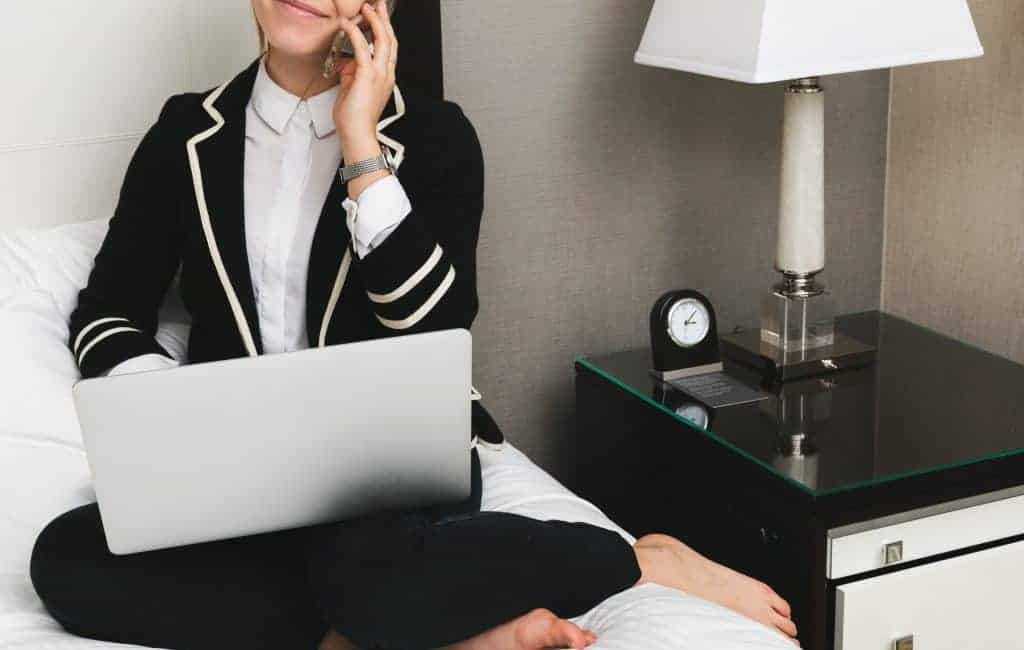 woman with laptop sitting in a hotel bed