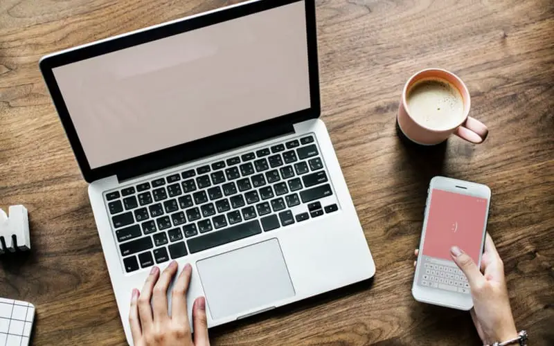 laptop on desk with pink mobile screen