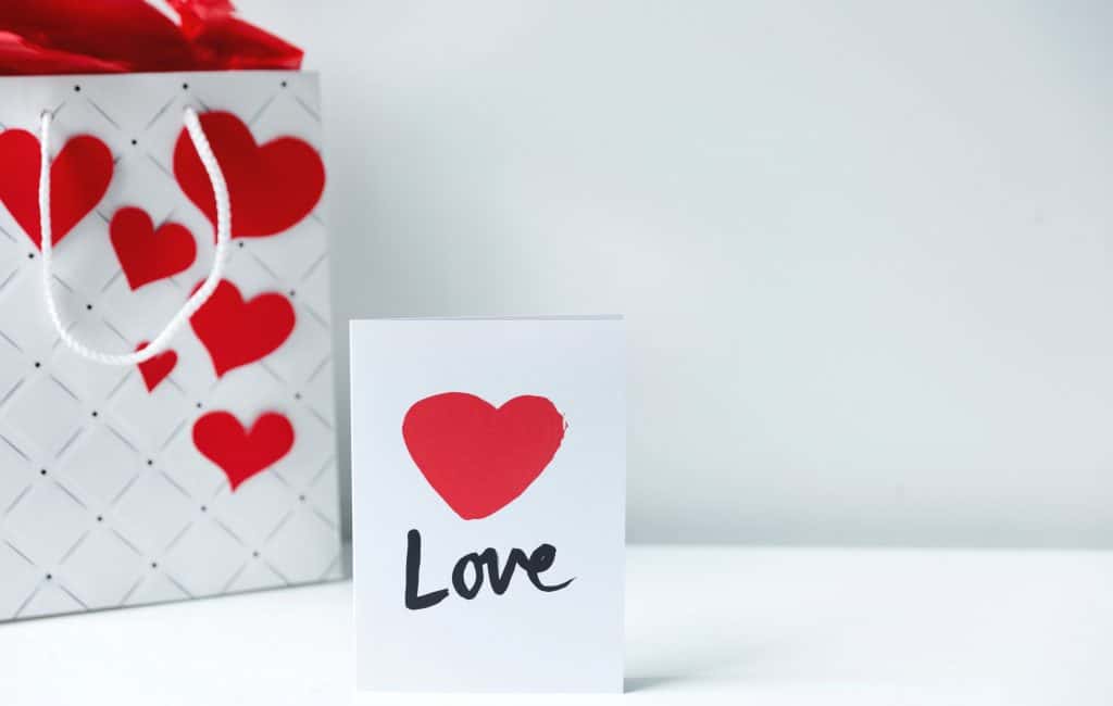 white paper bag with attached red heart shape paper and a Valentines Card