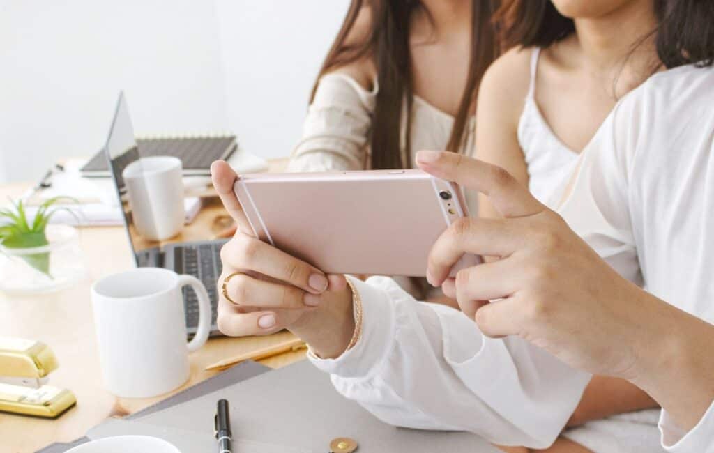 woman's hand holding a pink smart phone