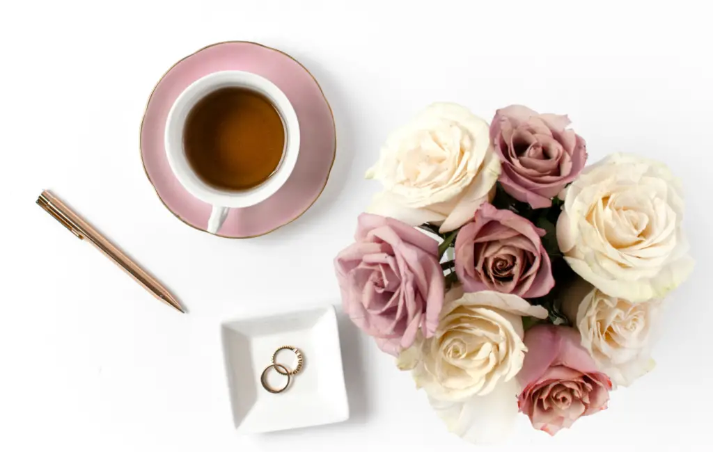 a photo of  a coffee, pen, rings and flower