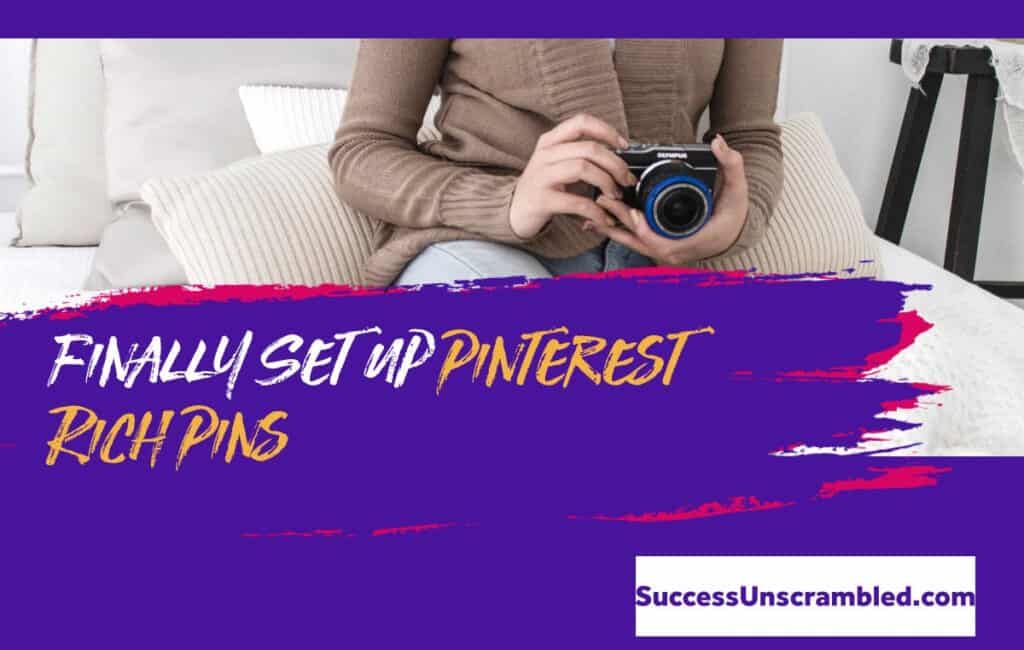 woman wearing brown cardigan holding a camera while sitting on her bed