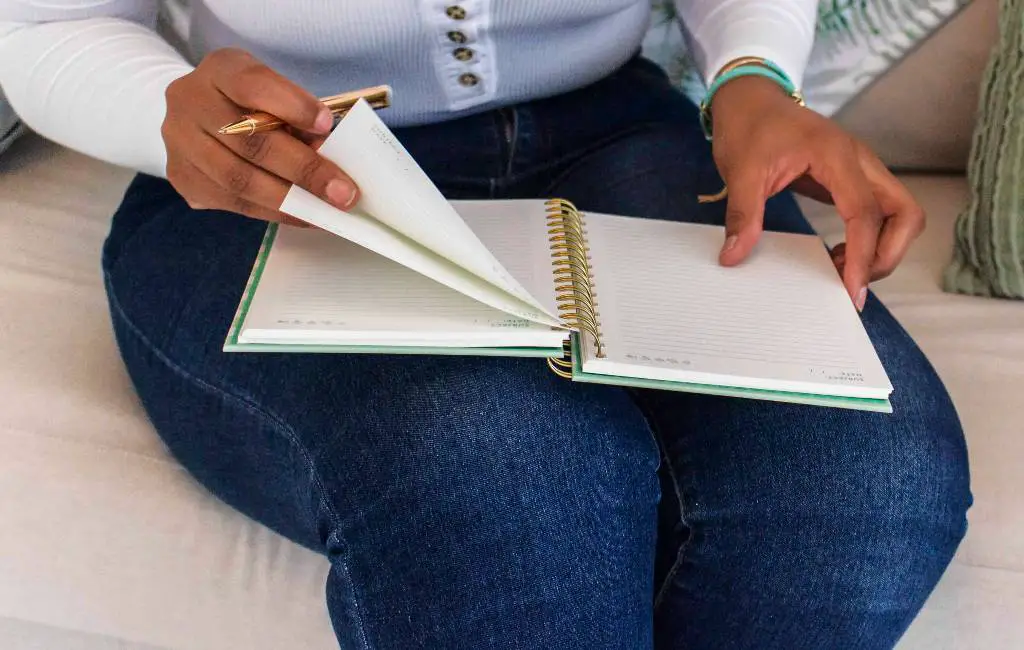 woman seating on coach flipping a notebook on her lap