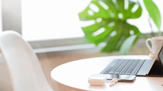 laptop next to a phone and earphones on a round table