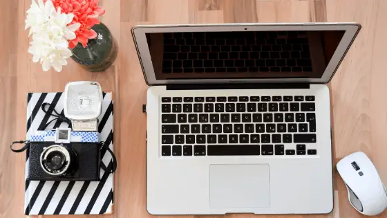 laptop next to a flower vase and a vintage camera