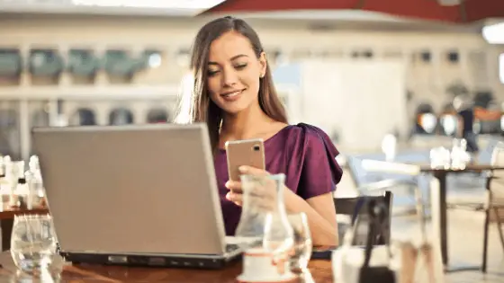 woman using her laptop and phone on a coffee shop