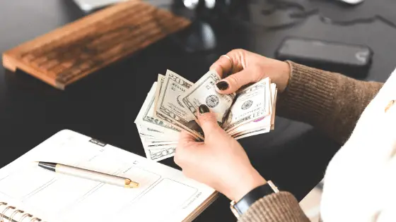 a hand of a woman counting dollar bills