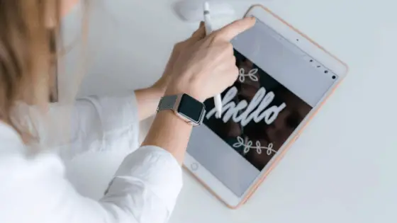 woman's hand holding a stylus pen and a tablet