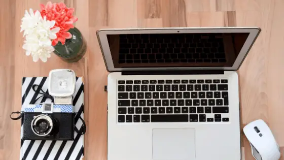 laptop next to a flower vase and a vintage camera