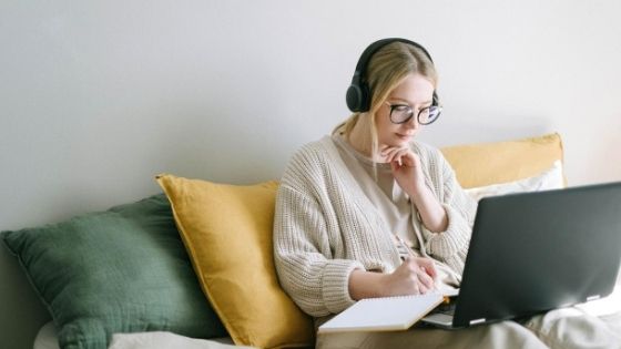 a woman with headphone on writing notes