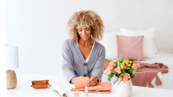 woman doing art craft on her white desk near her bed