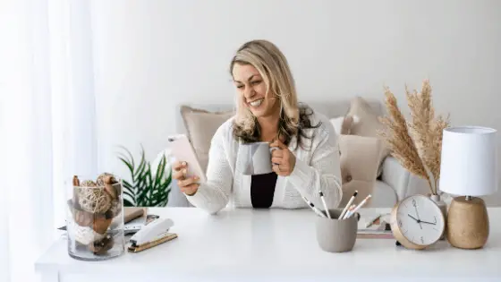 woman holding a mug smiling through her phone