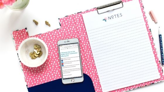 a note paper clip on a pink folder next to a smart phone