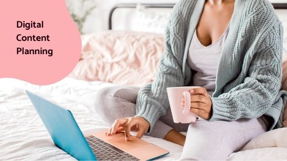 woman sitting on bed while working and sipping hot beverage