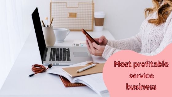 woman sitting on her working space while using her phone with brown phone case