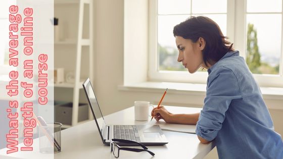 a photo of a woman sitting at a desk looking intently into her laptop screen with a writing instrument in her hand, coffee mug and glasses on the table