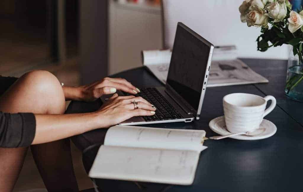 a photo of a laptop next to a notebook and coffee mug