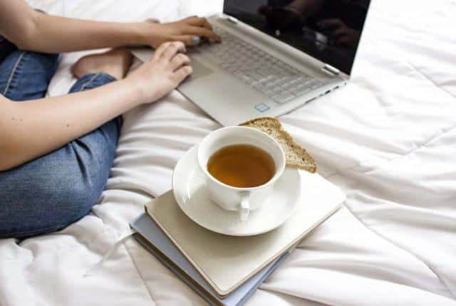 woman working in bed while drinking tea