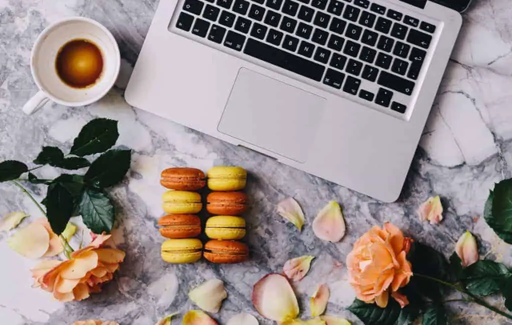 a photo of a laptop next to a tea and colorful macarons