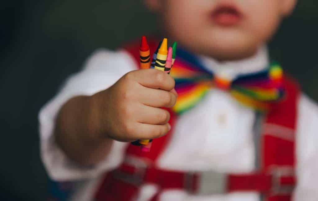 little boy holding crayons