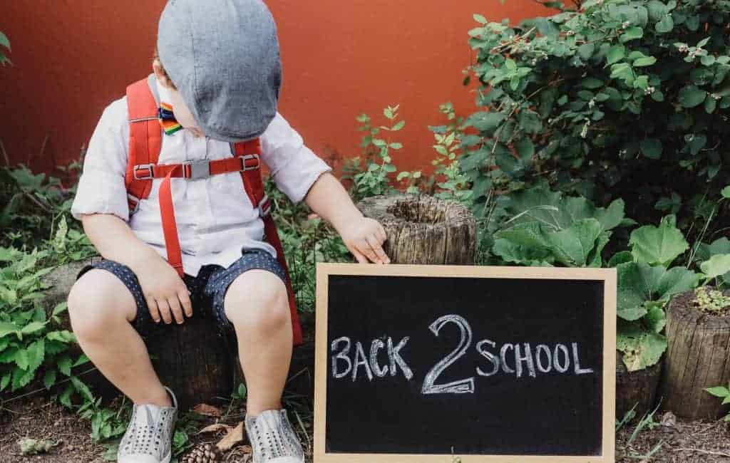 a boy holding a back 2 school sign