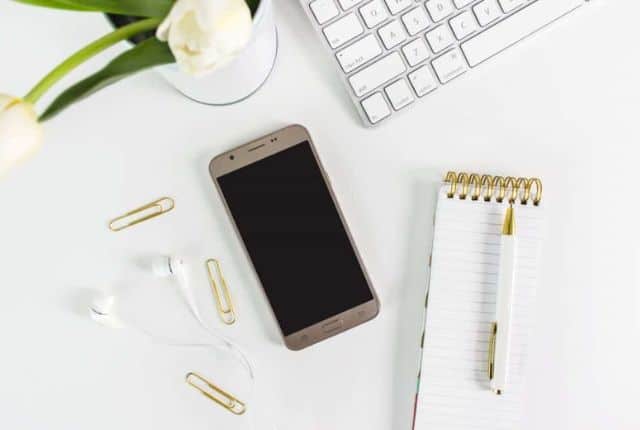 phone, white earphone, a notebook in a desk