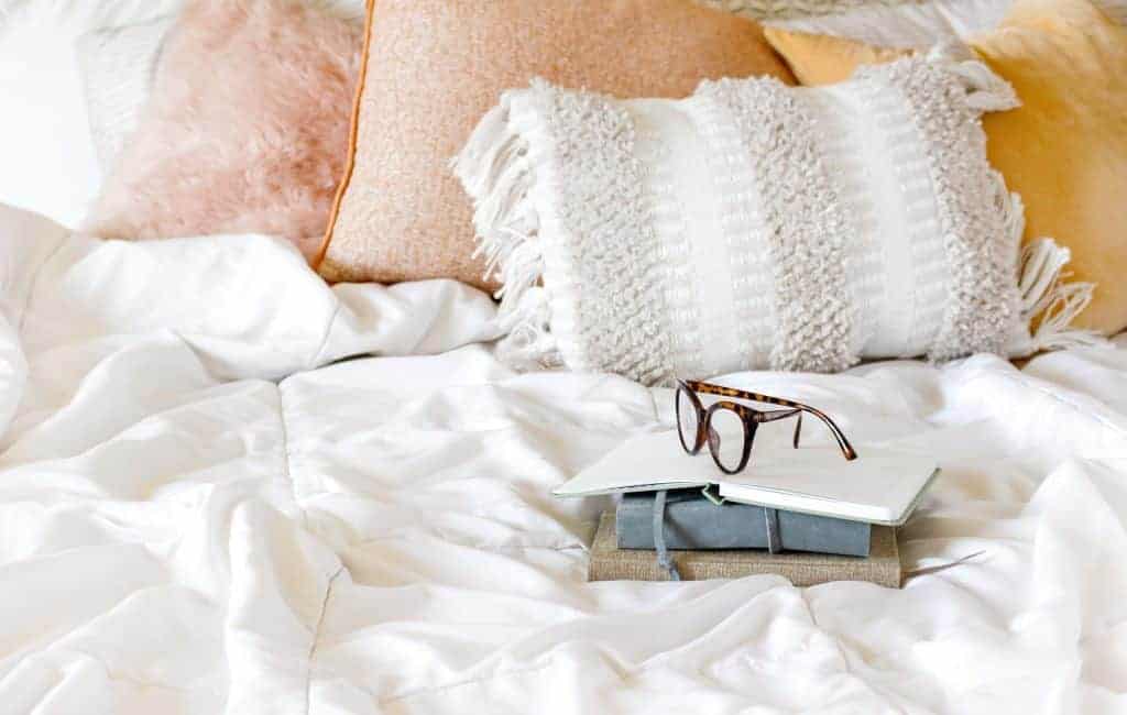 eyeglasses on a pile of notebooks in a bed