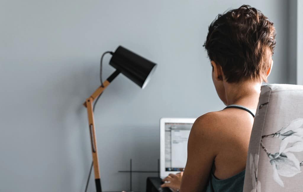 woman who's back is turned typing on her laptop placed on her desk