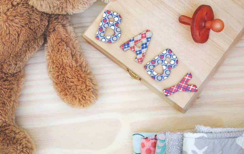 teddy bear and pacifier next to a letters B, A, B, Y