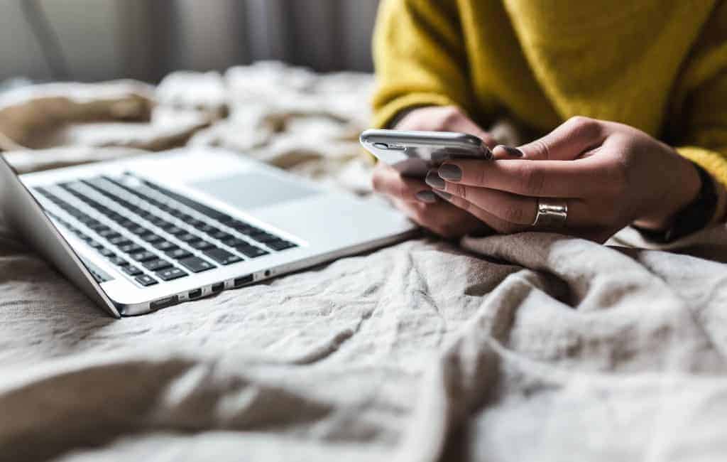 woman lying down the bed using her phone