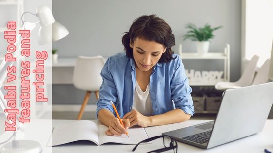 photo of a woman scribble notes in a book next to a laptop - Podia vs Kajabi