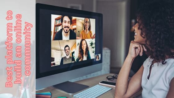 A photo of a large desktop screen with people having a live meeting and a woman sitting chatting with them